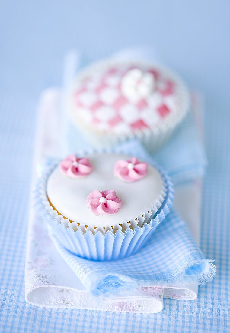 Two glazed cupcakes and candy flowers