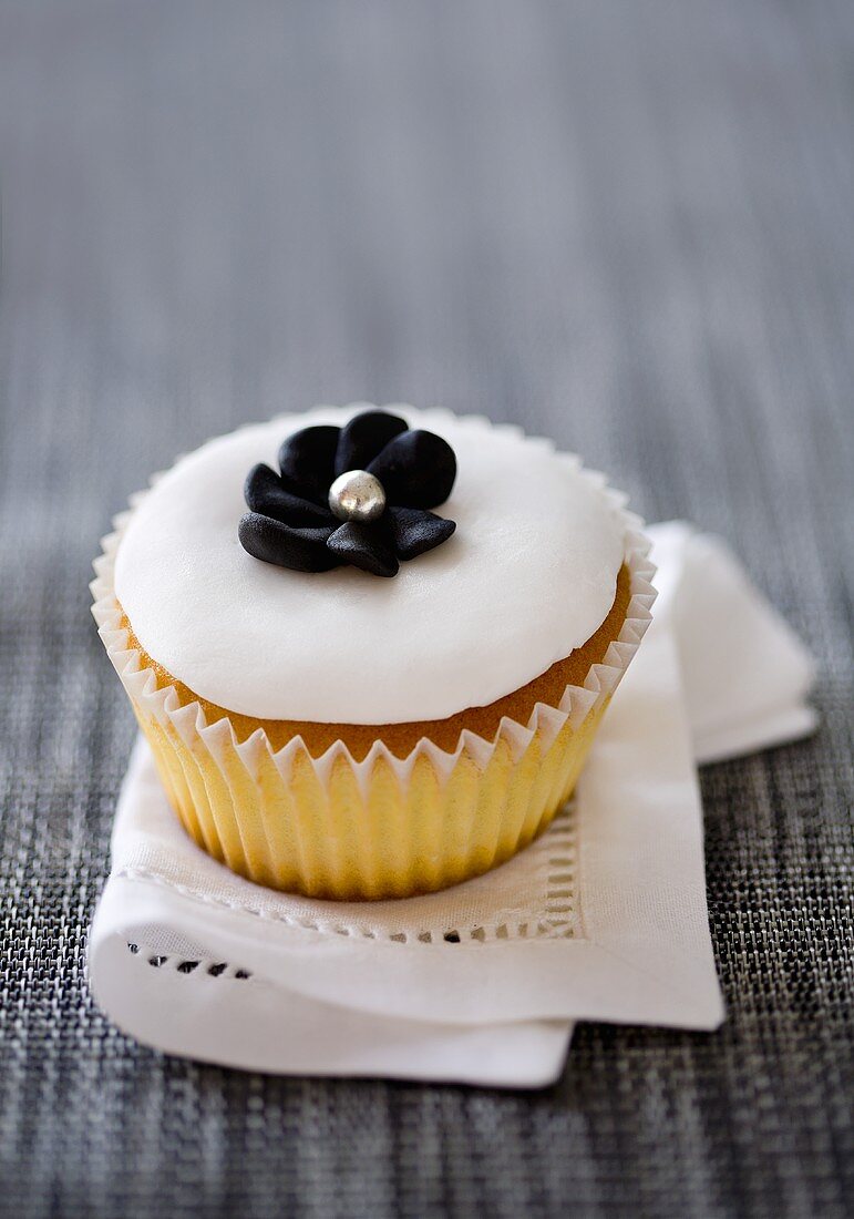 Cupcake mit weisser Glasur und schwarzer Zuckeblüte