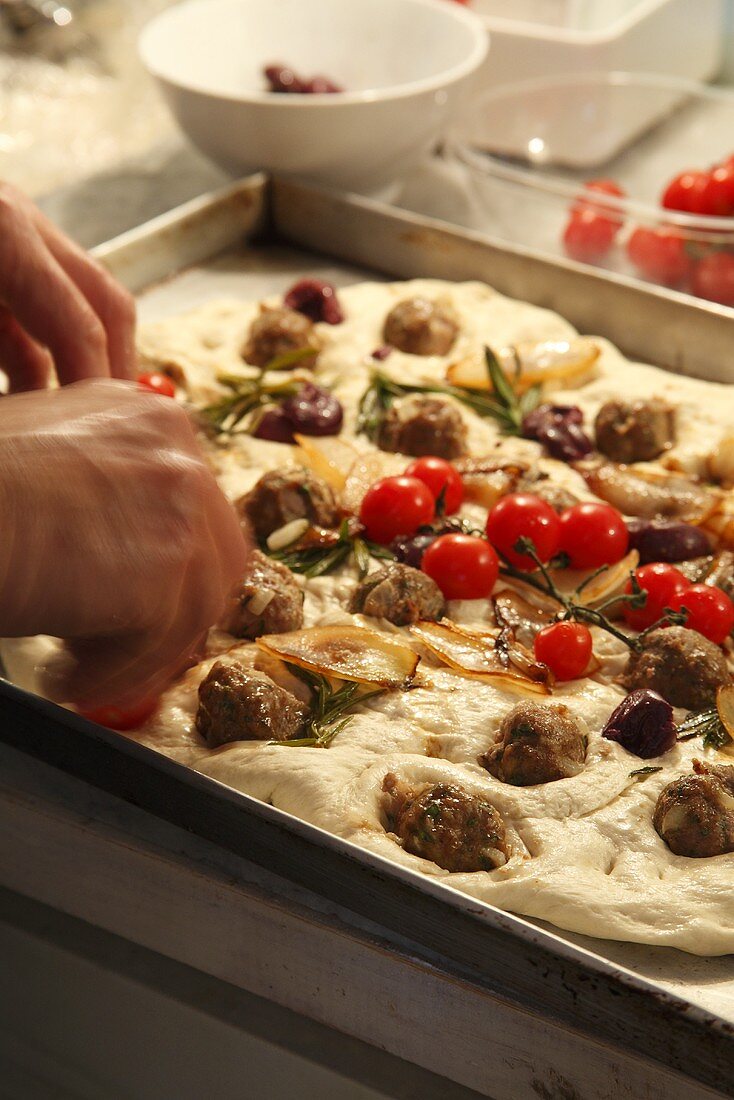 Preparing flatbread with meatballs, tomatoes and caramelised onions