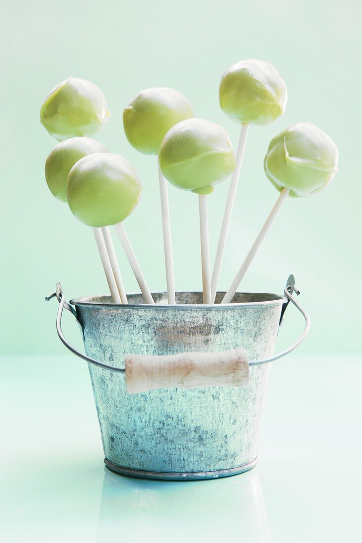 Light green cake pops in a small bucket