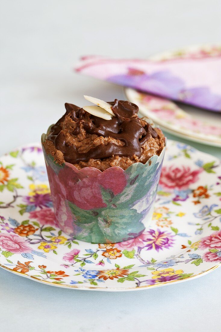 A chocolate cupcake in a paper case printed with flowers