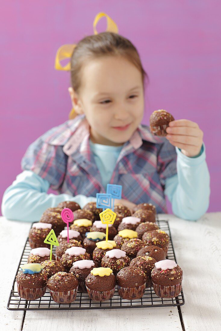 A girl eating a mini chocolate cupcake