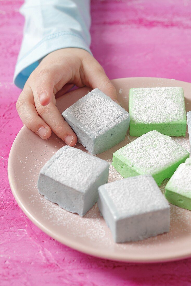 Kinderhand greift nach selbstgemachten Marshmallows