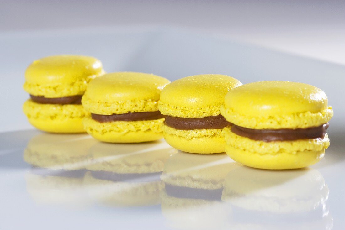 Four yellow macaroons with chocolate cream