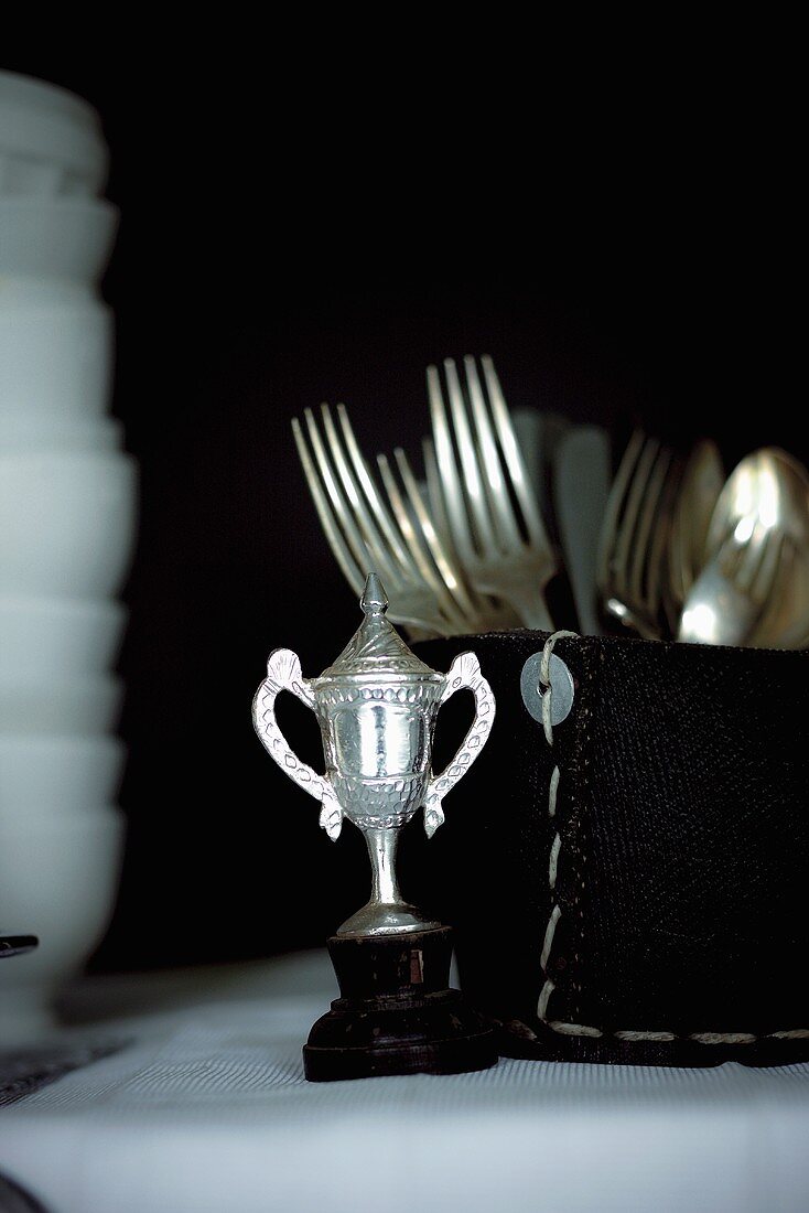 A mini trophy, cutlery and crockery on a buffet table