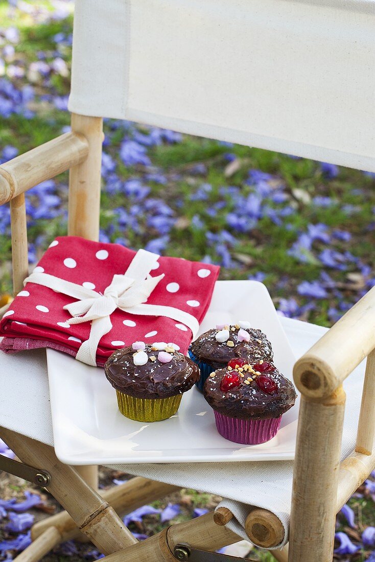 Schokoladencupcakes und Stoffservietten auf Stuhl