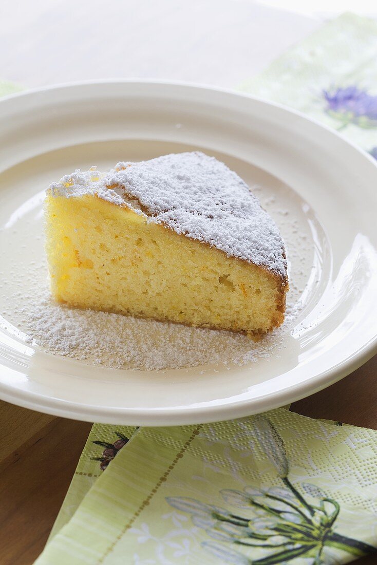 A slice of olive oil cake with icing sugar