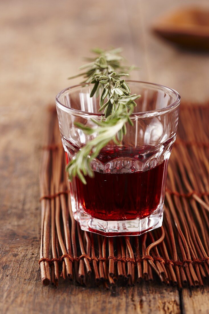 A sprig on rosemary on a glass of red wine
