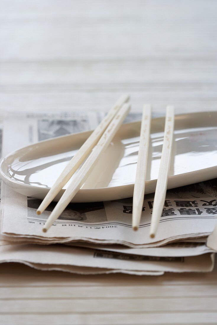 A plate and chopsticks on an Asian newspaper