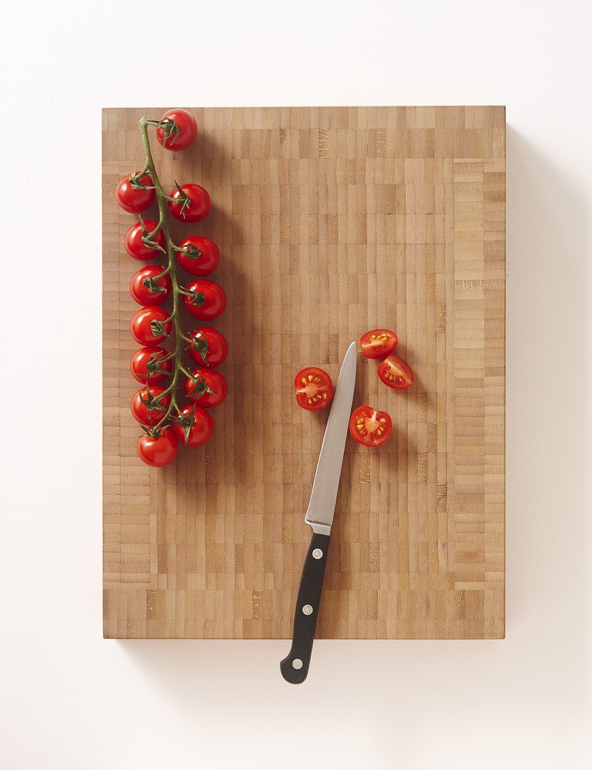 Cherry tomatoes with a knife on a chopping board