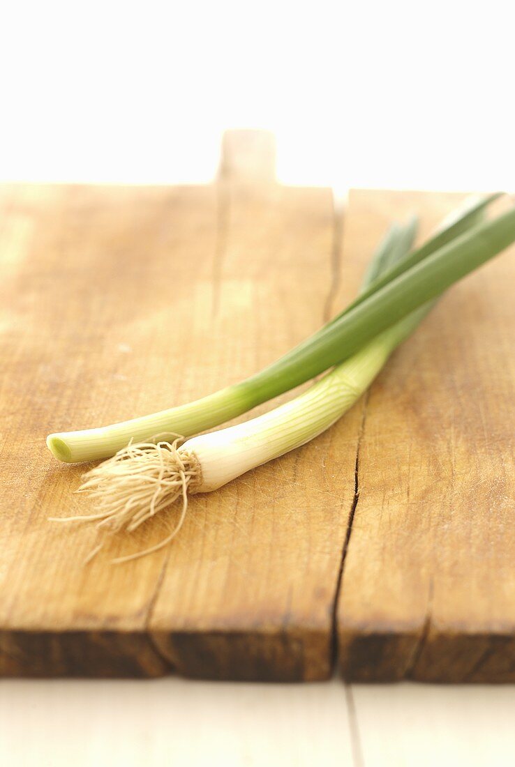 Two spring onions on a chopping board