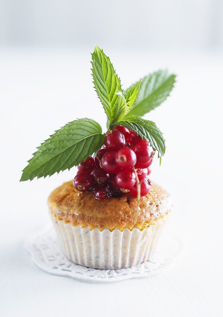 A muffin topped with redcurrants and mint