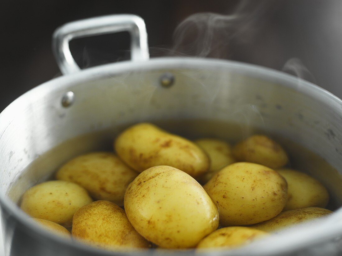 Gekochte Pellkartoffeln im dampfenden Wasser