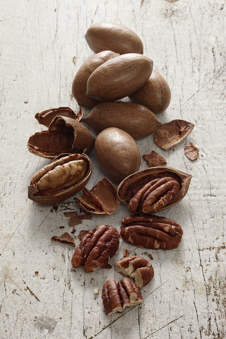 Pecan nuts, with and without shells, on a white wooden surface