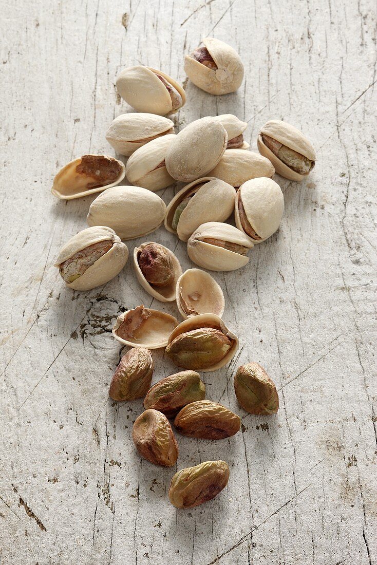 Pistachios, with and without shells, on a white wooden surface