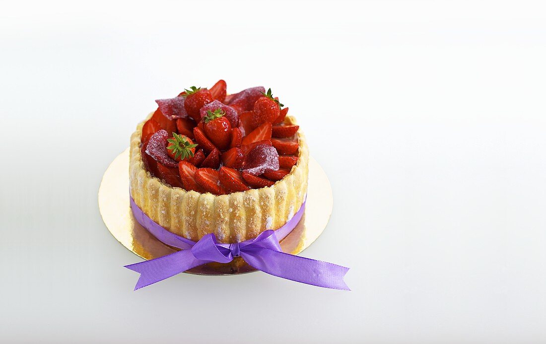 A mini strawberry tart with a purple bow