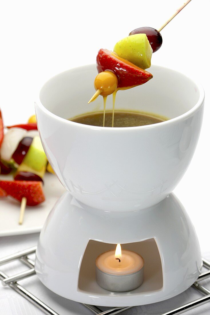 A butterscotch fondue with fruit kebabs