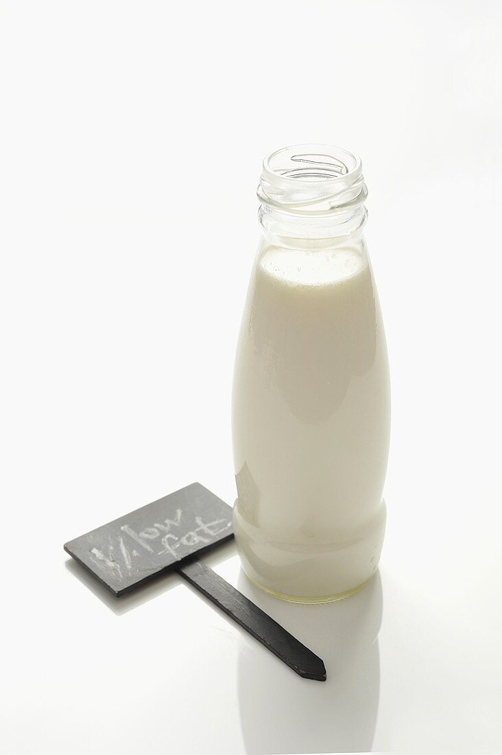 Fettarme Milch in Flasche, daneben Schild