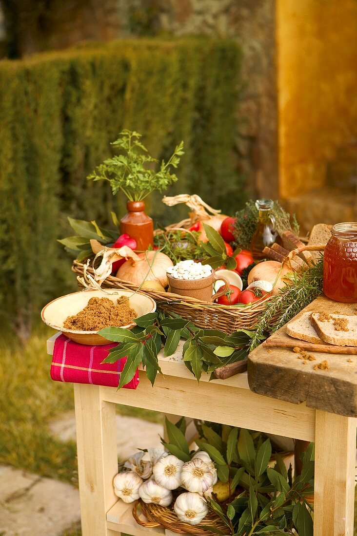 A garden table laid with vegetables, bread, spreads, herbs and honey