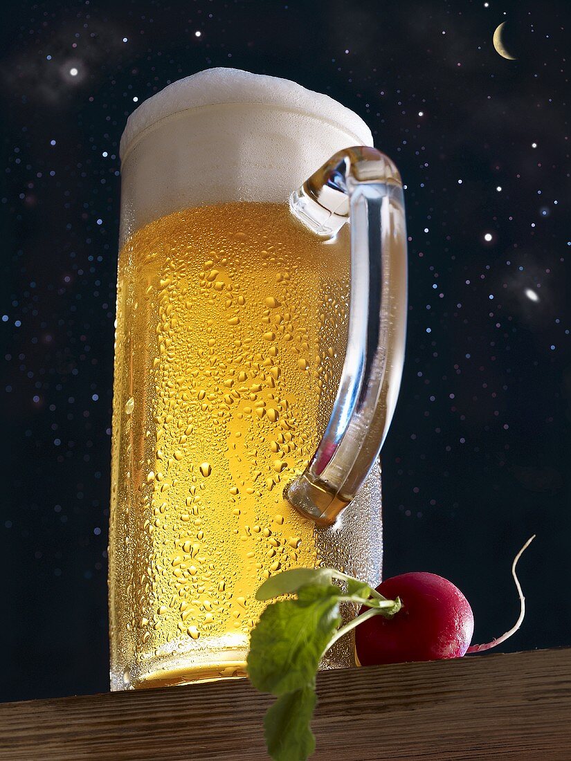 Helles Bier im Glaskrug und Radieschen vor Sternenhimmel