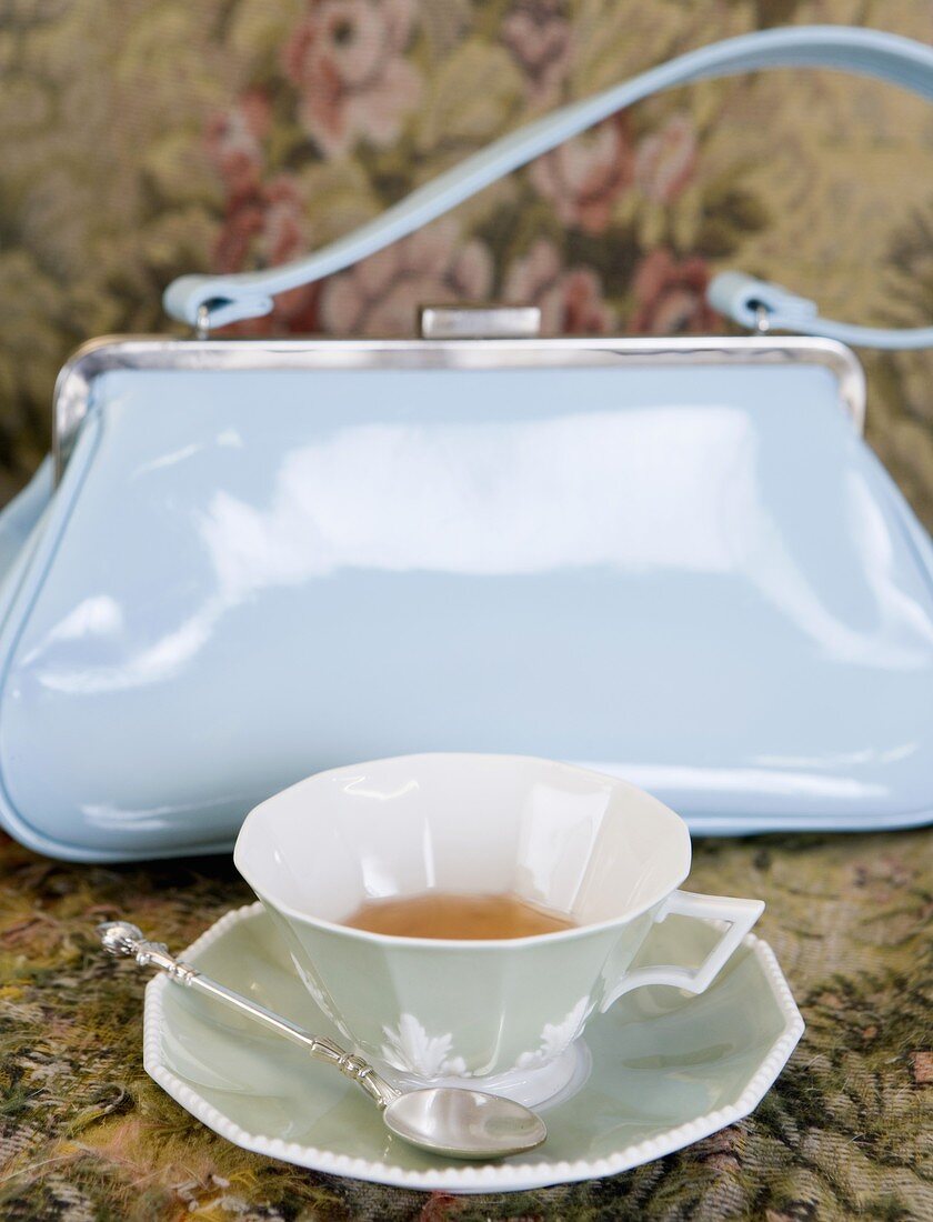Tea cup in front of a handbag