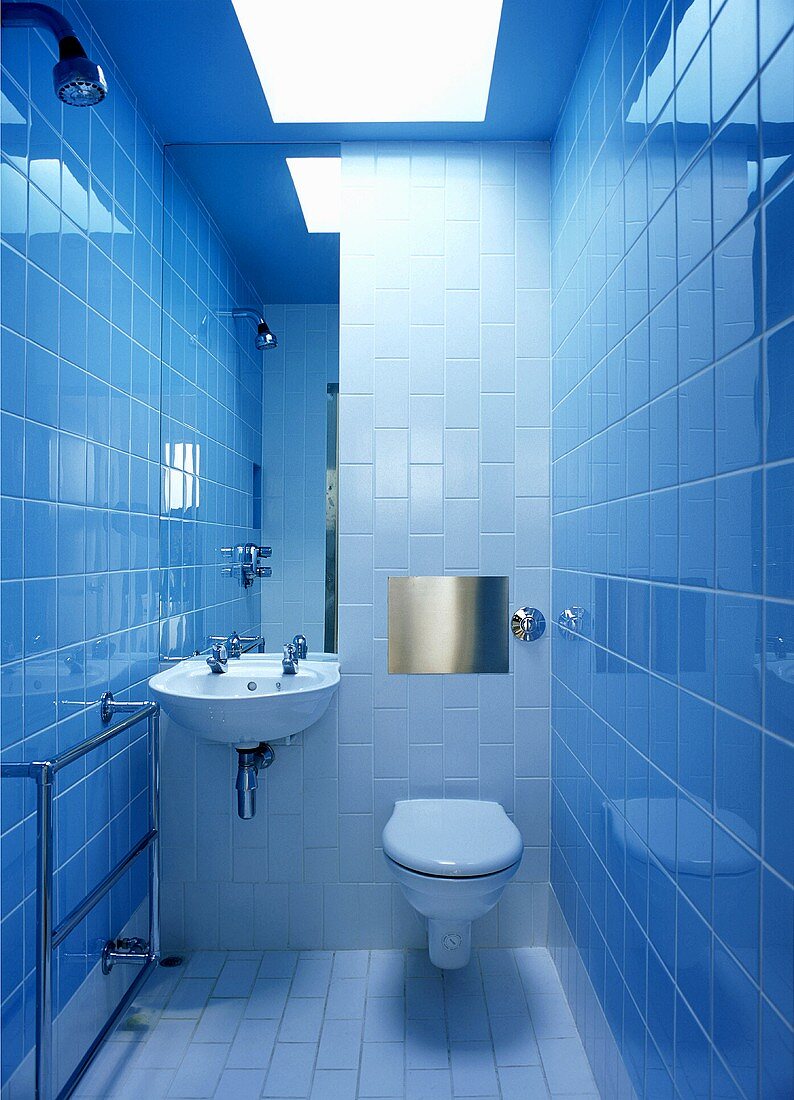 A modern tiled bathroom with a toilet, a basin and a skylight