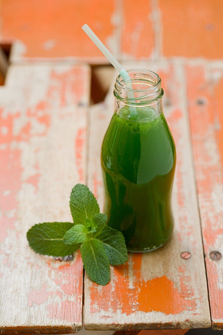A cucumber smoothie in a bottle with a straw