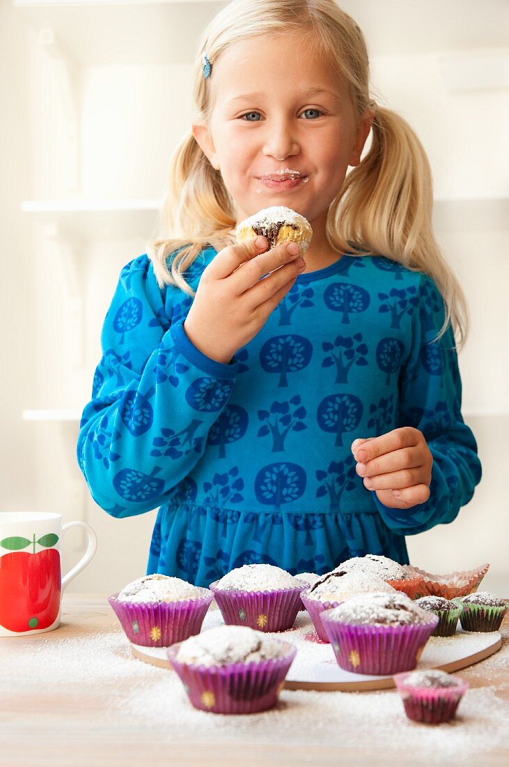 Blondes Mädchen isst ein Muffin