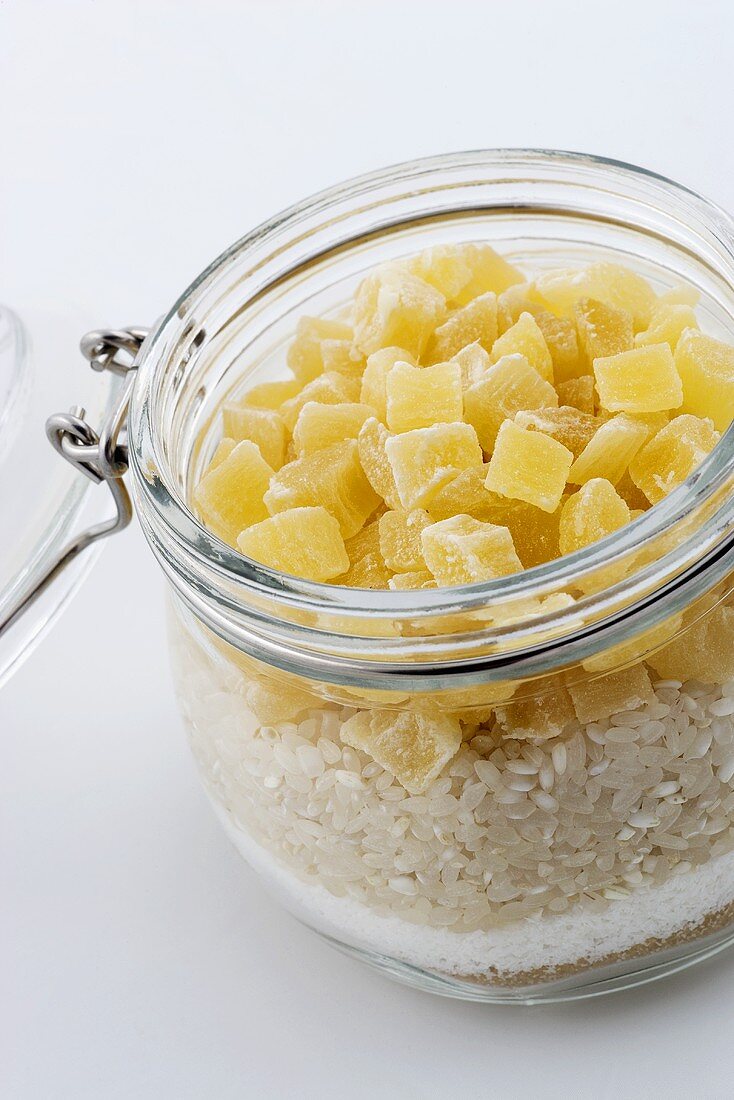 Vorratsglas mit braunem Zucker, Kokosraspeln, Reis und getrockneten Ananasstückchen