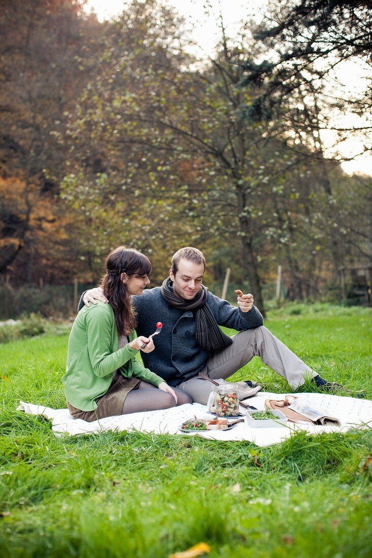 A couple having a picnic in a field in autumn