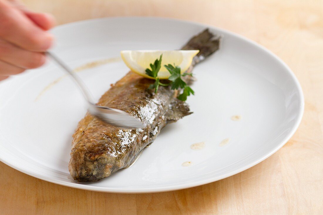 Fried trout being drizzled with melted butter