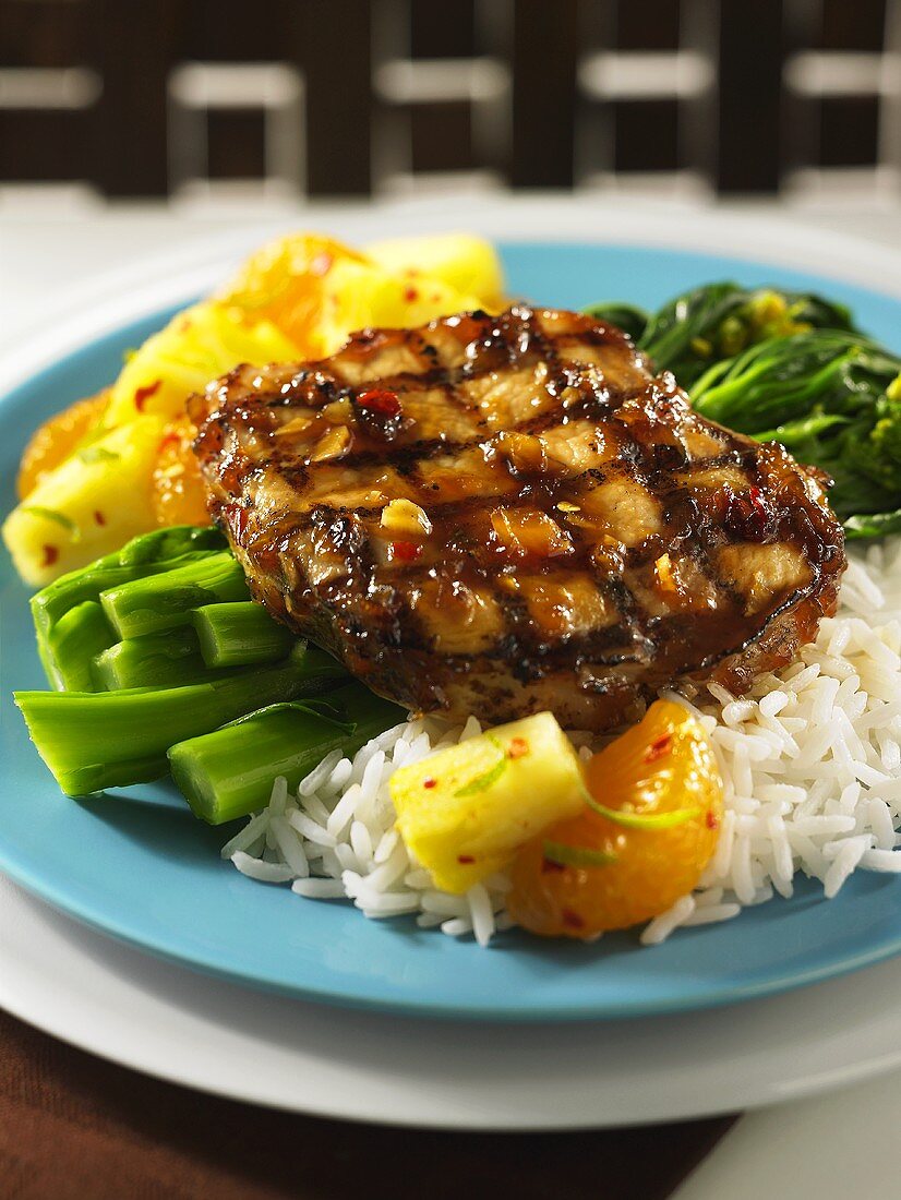 A pork chop with a pineapple glaze, rice and pineapple pieces