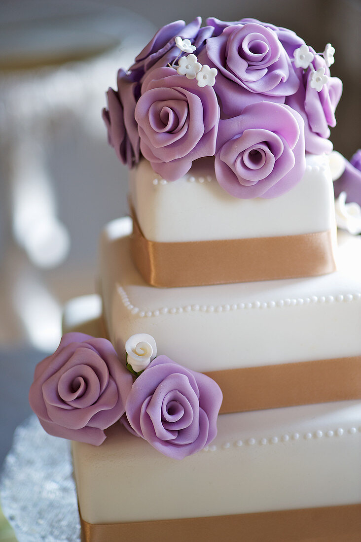 A three tier wedding cake with purple marzipan roses