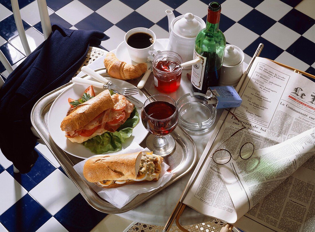 Bistrotisch mit belegten Baguettes, Wein, Kaffee, Croissant