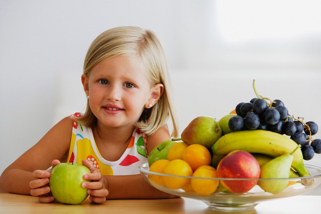 Little girl and full fruit bowl