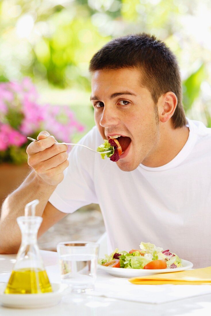 Young man eating salad