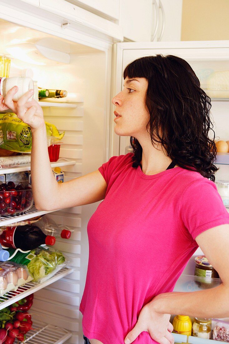 Junge Frau vor offenem Kühlschrank