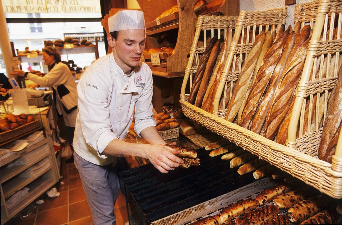 Bäcker legt Sortiment in Bäckerei aus