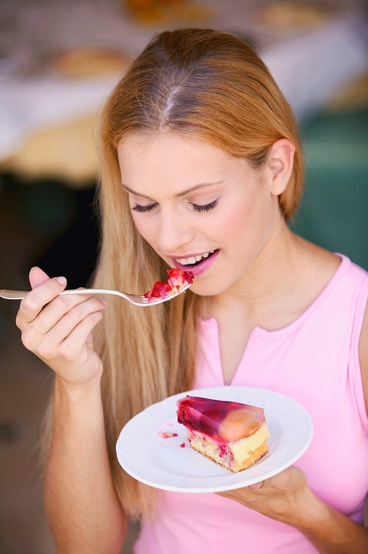 Junge Frau isst ein Stück Obstkuchen