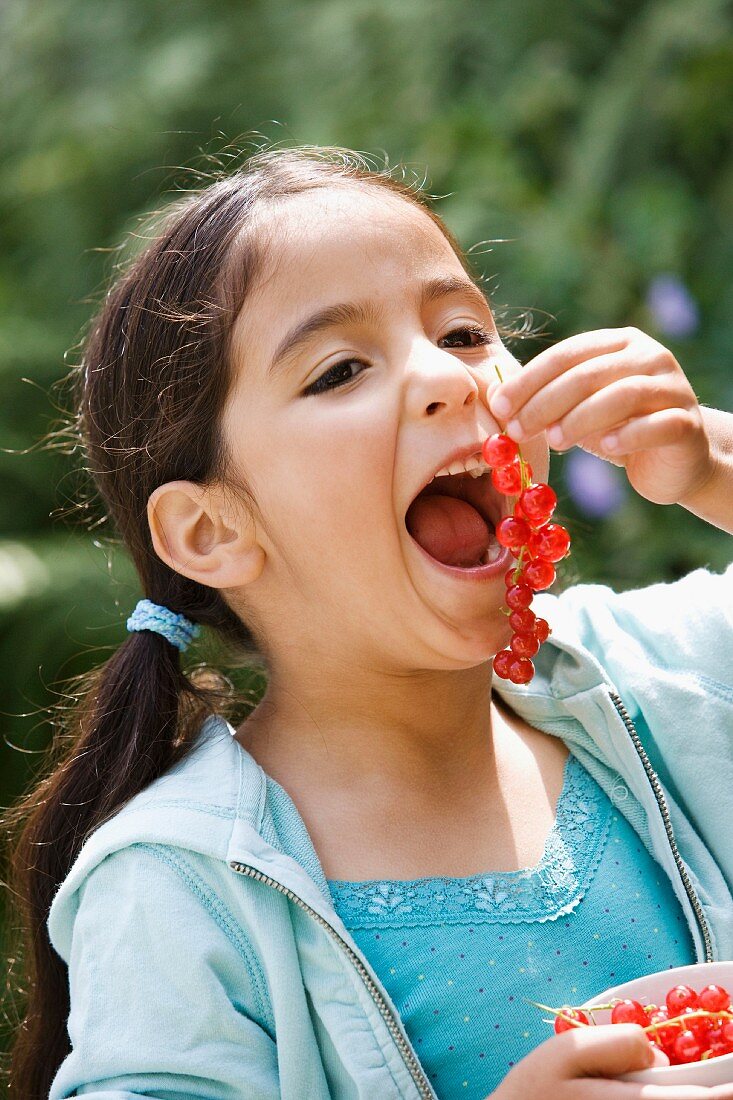 Mädchen isst rote Johannisbeeren