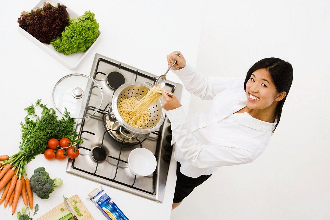 Junge Frau beim Abtropfen von Spaghetti