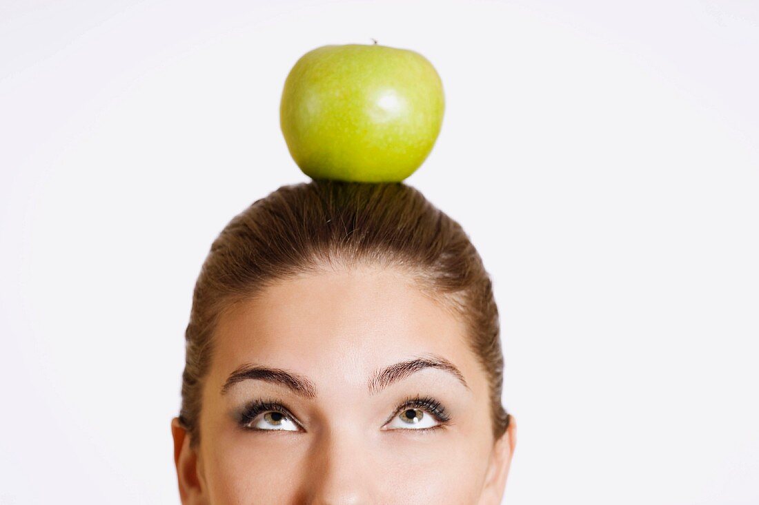 Young woman with an apple on her head