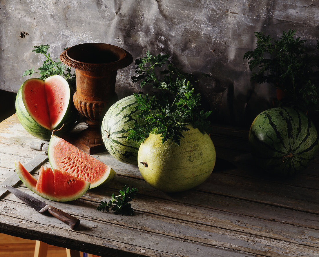 Ganze und aufgeschnittene Wassermelonen auf Holztisch
