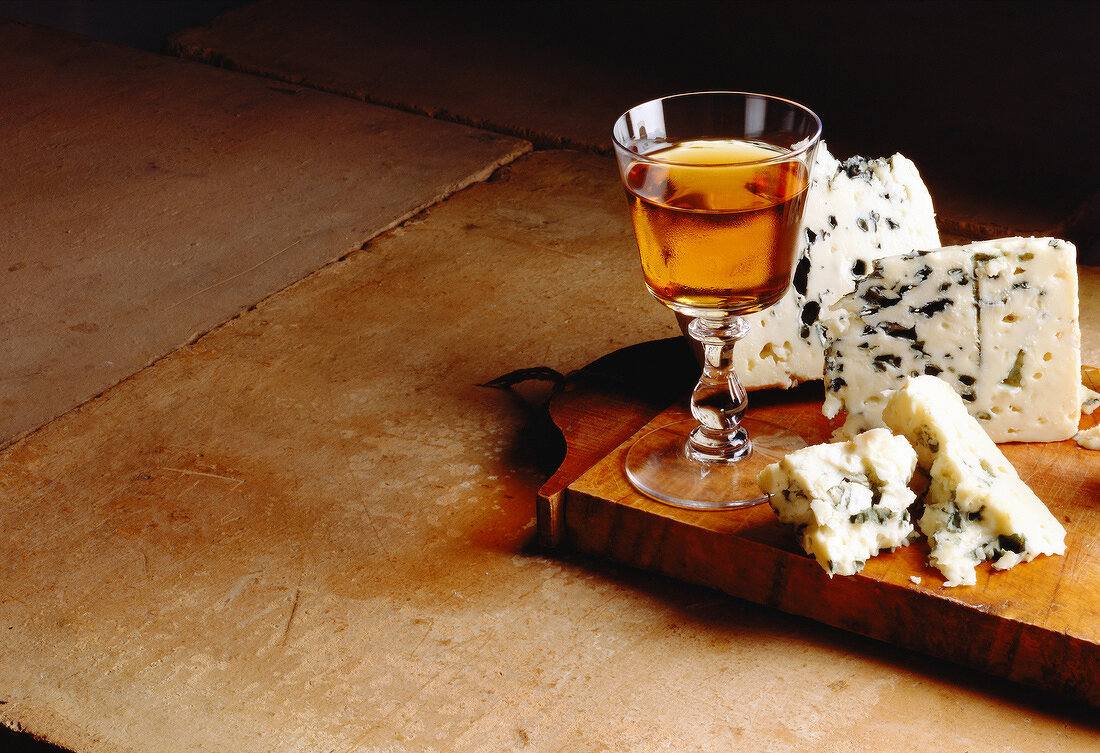Roquefort mit einem Glas Weißwein auf Holzbrett