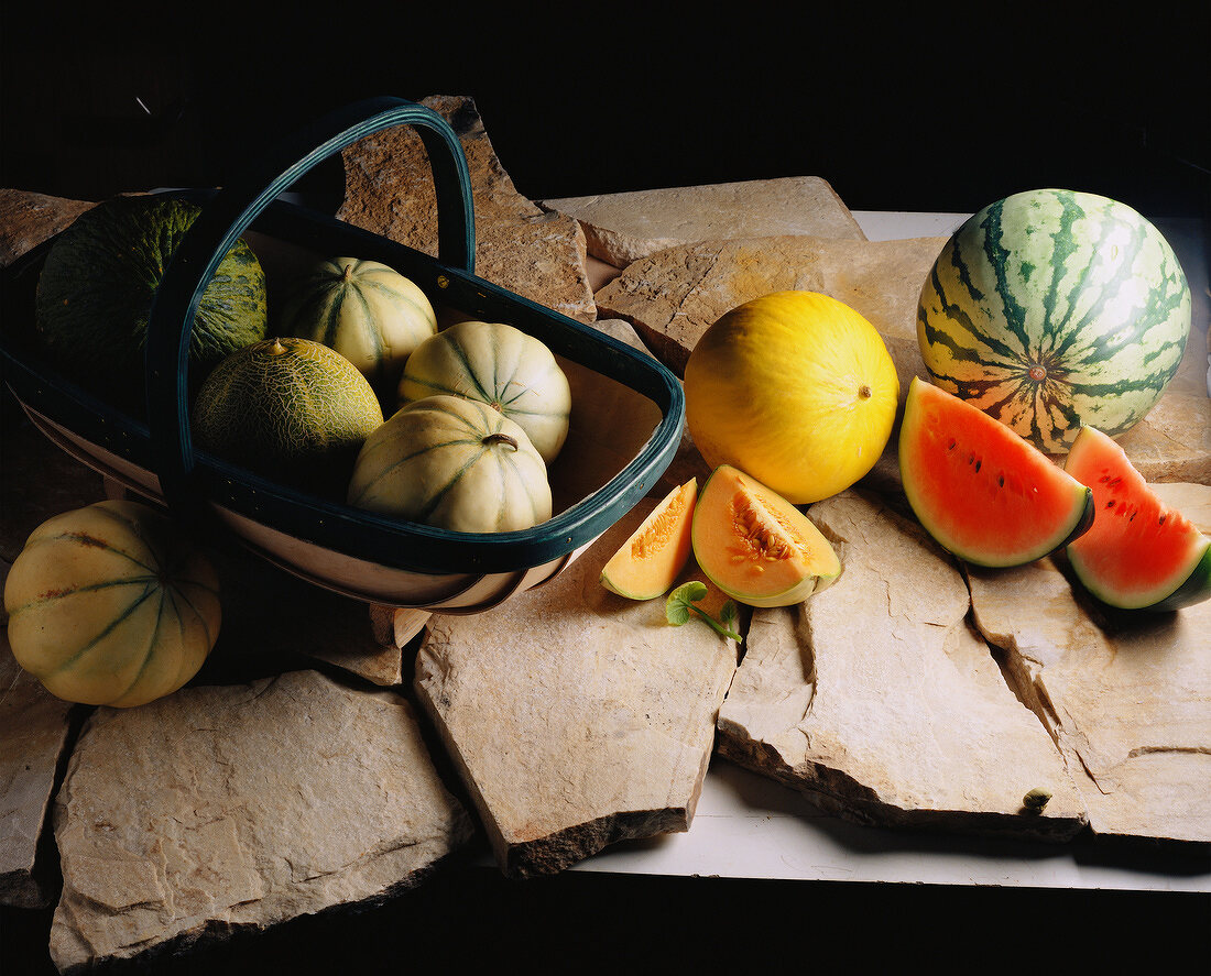 Verschiedene Melonensorten im Korb und auf Steinplatten