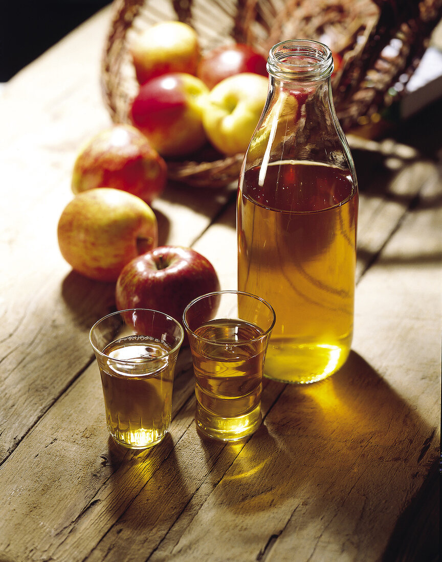 Frischer Apfelsaft und Gläsern und Flasche; Äpfel im Hintergrund