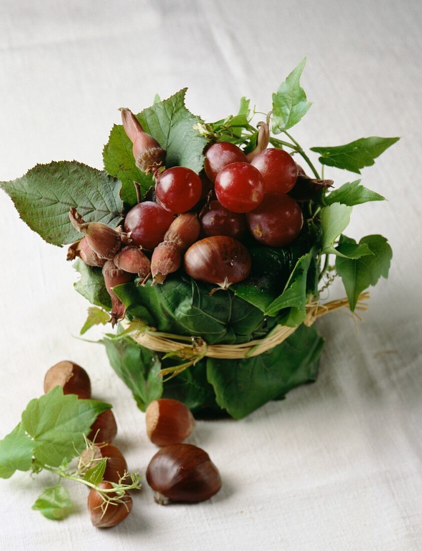Herbstliches Tischgesteck mit Trauben, Haselnüssen und Maroni