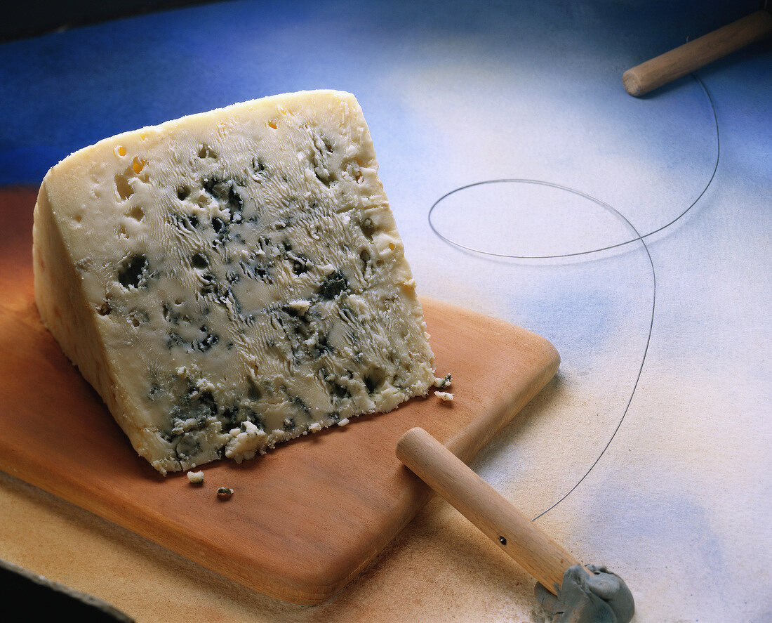 Ein Stück Roquefort auf einem Holzbrett mit Schneidedraht