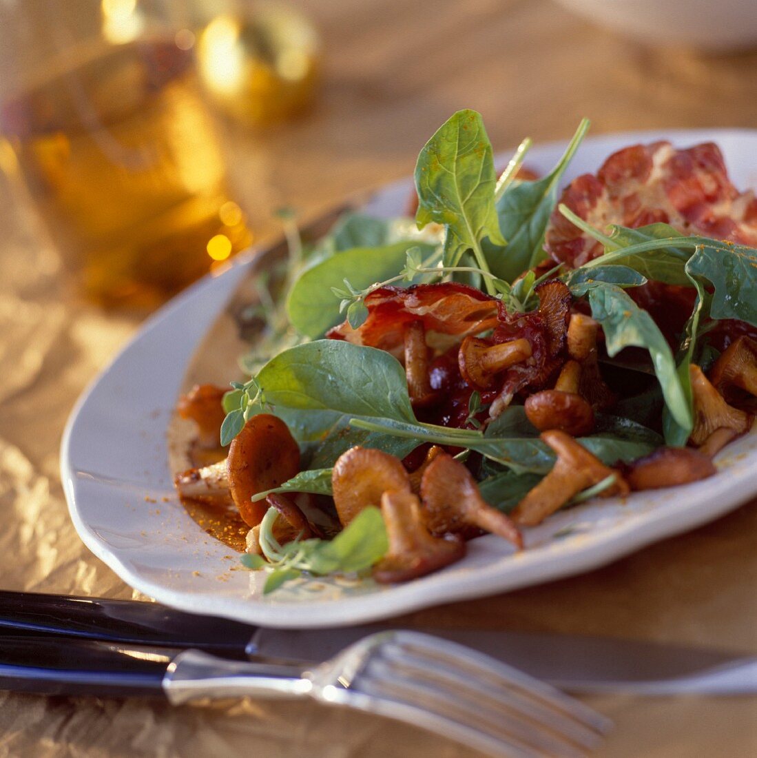 Chanterelle salad with spinach leaves and grilled coppa