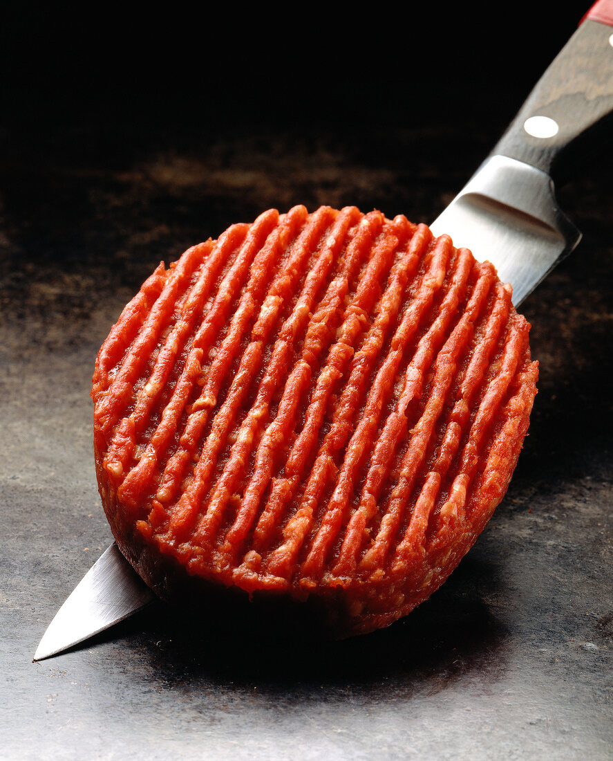 Rohes Rindfleisch-Patty auf einem Küchenmesser
